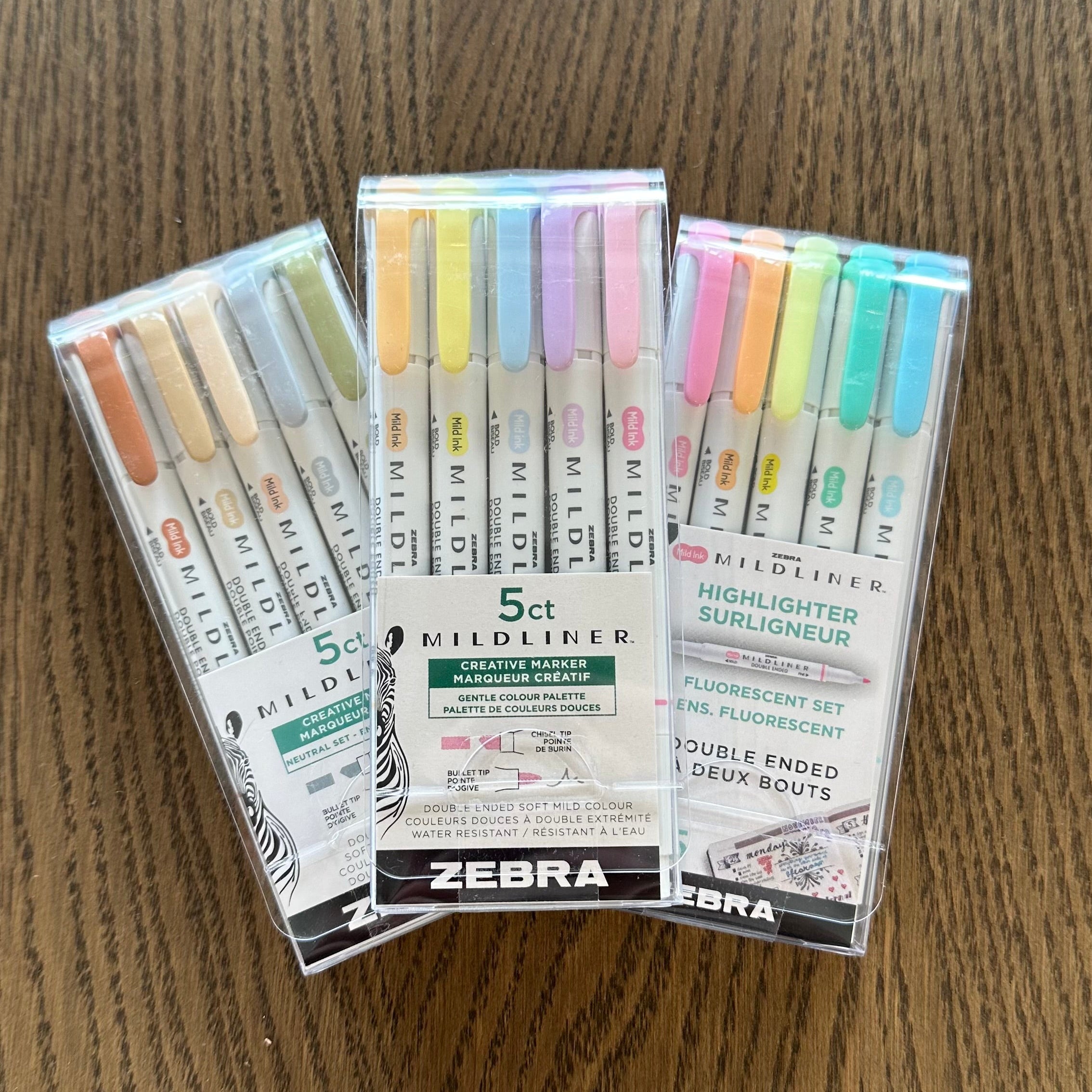 Three packages of Zebra highlighters on a wooden surface